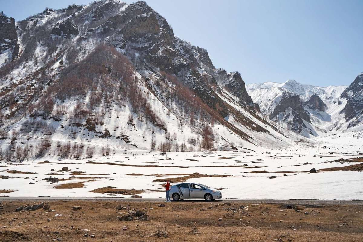 a car on a road with a snow-capped mountain in the background