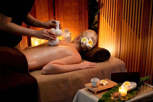 A body massage with hot herbal balls, the masseur gently squeezes a bag of herbs on a woman's body