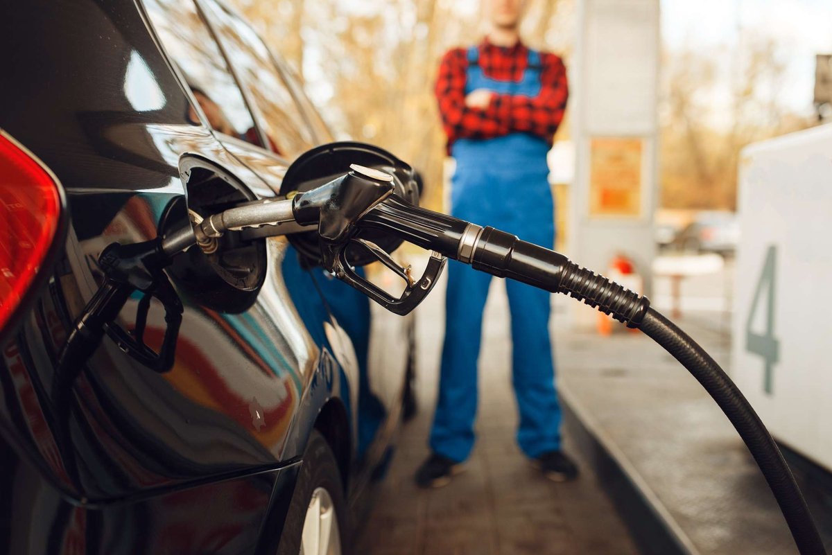 A gas station attendant stands next to a car at a gas station