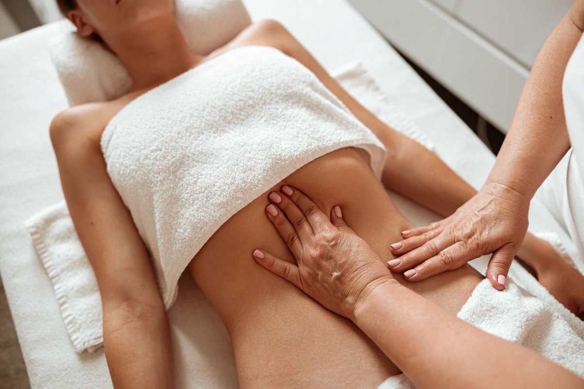 A masseuse massages a client's stomach.