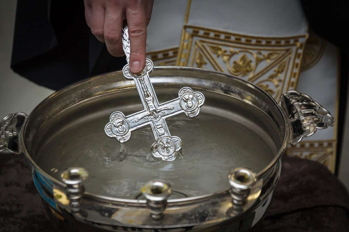 A priest dips a religious cross into holy water at the Epiphany in a Georgian church.