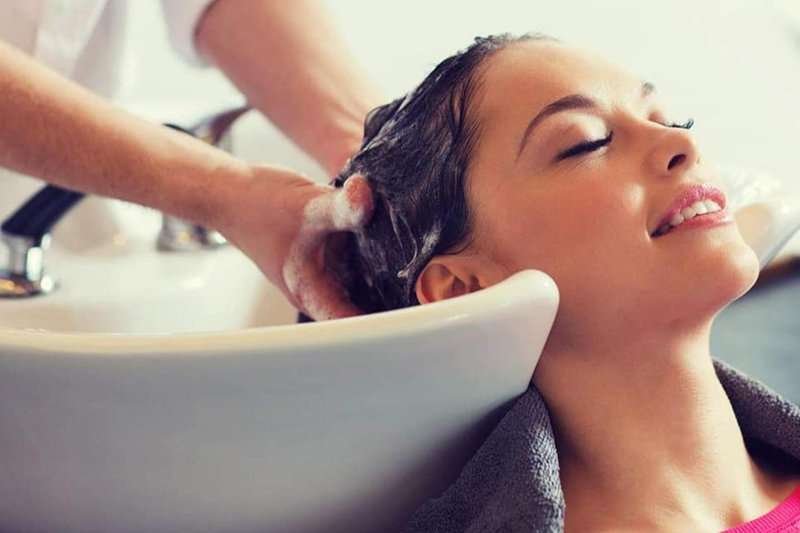 A hairdresser washes a girl's hair