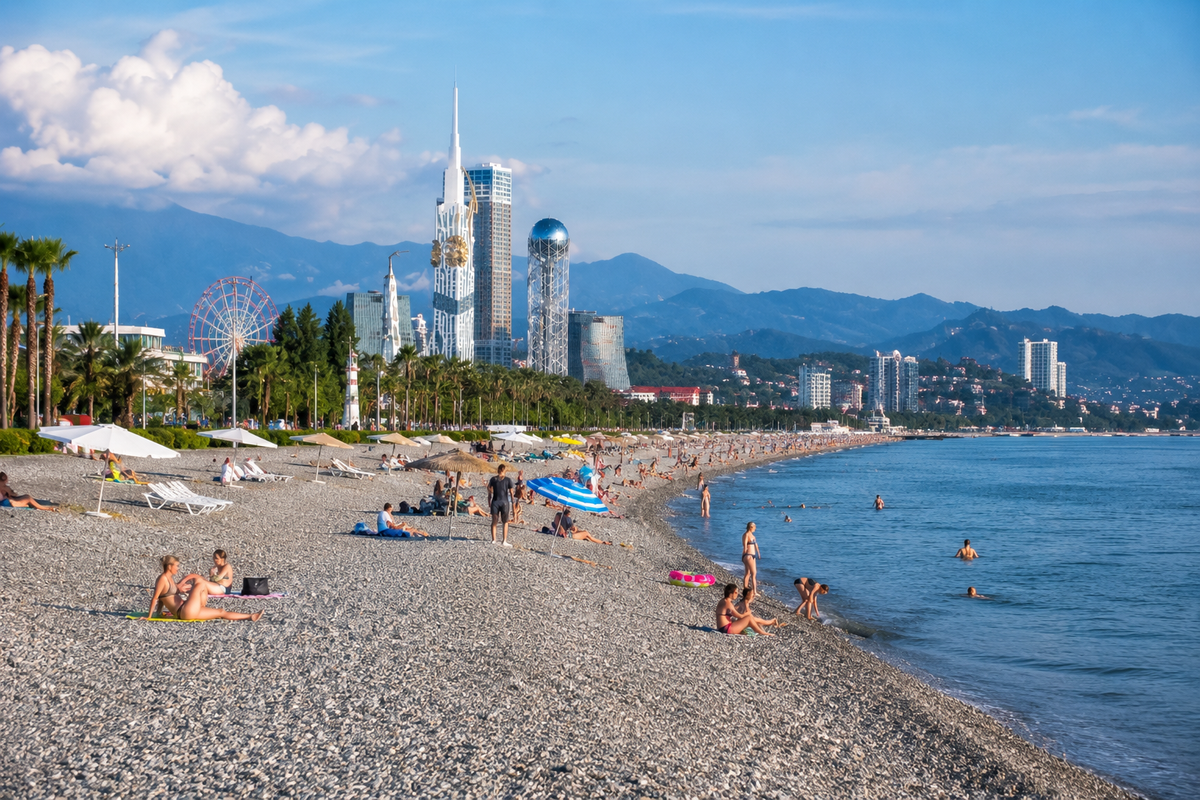 A wide view of Batumi’s famous pebble coastline with the Black Sea, Batumi Boulevard, modern skyscrapers and beachgoers enjoying the shore.