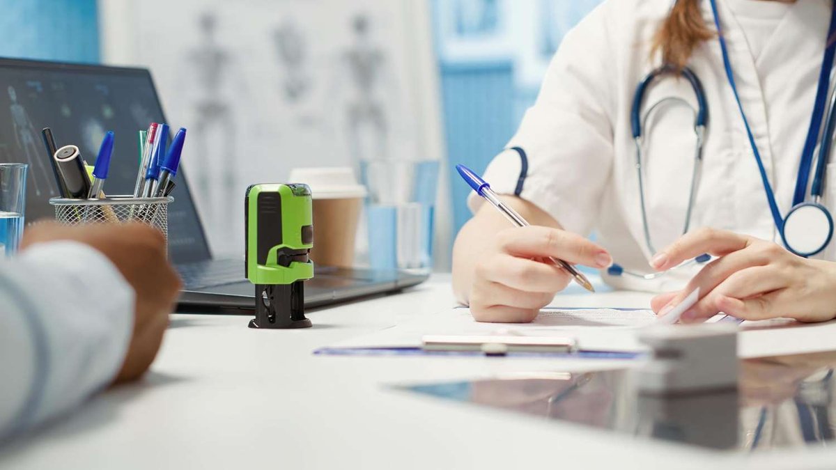 A doctor reviews paperwork with a patient at a clinic desk, illustrating a consultation covered under resident medical insurance.