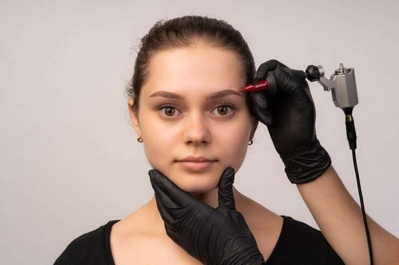 A cosmetologist applying permanent makeup to eyebrows