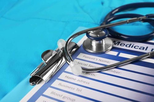 Medical stethoscope and paper on blue background