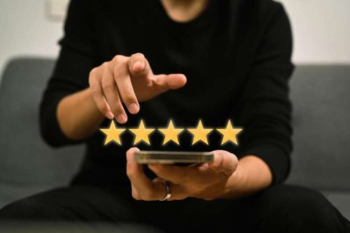 A man uses a smartphone and leaves a positive review on Google Maps