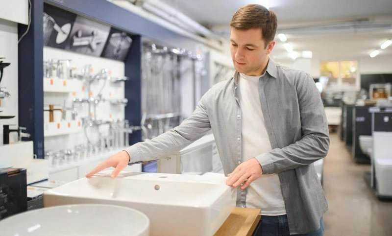 A man in a plumbing store chooses a bathroom sink.