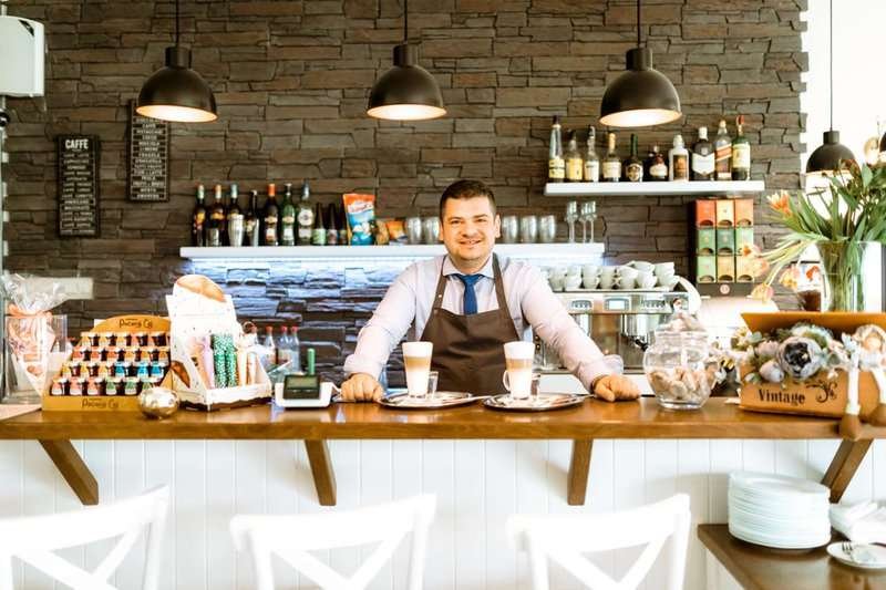 A waiter at the bar with glasses of cappuccino in a cafe bar