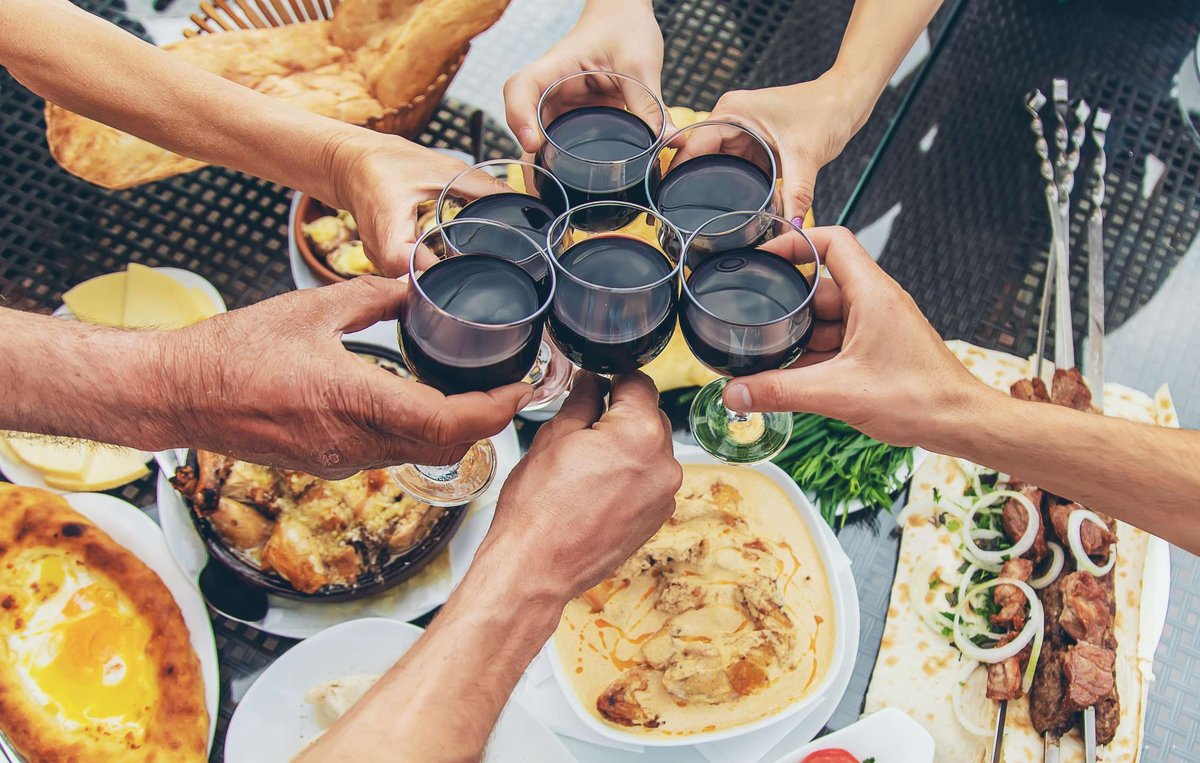 People clink glasses of wine against a backdrop of traditional Georgian dishes.