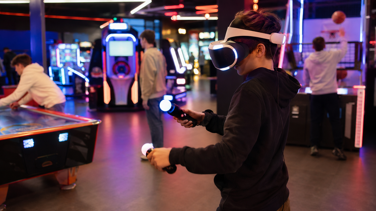 Teenagers playing at a virtual reality and arcade zone in an entertainment centre.