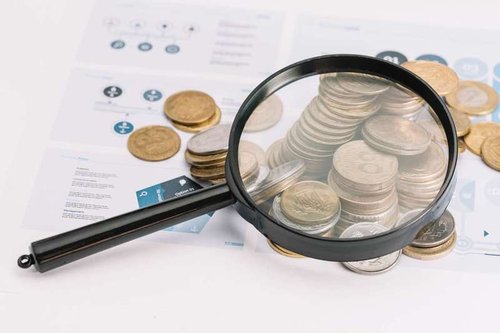A magnifying glass over fallen coins
