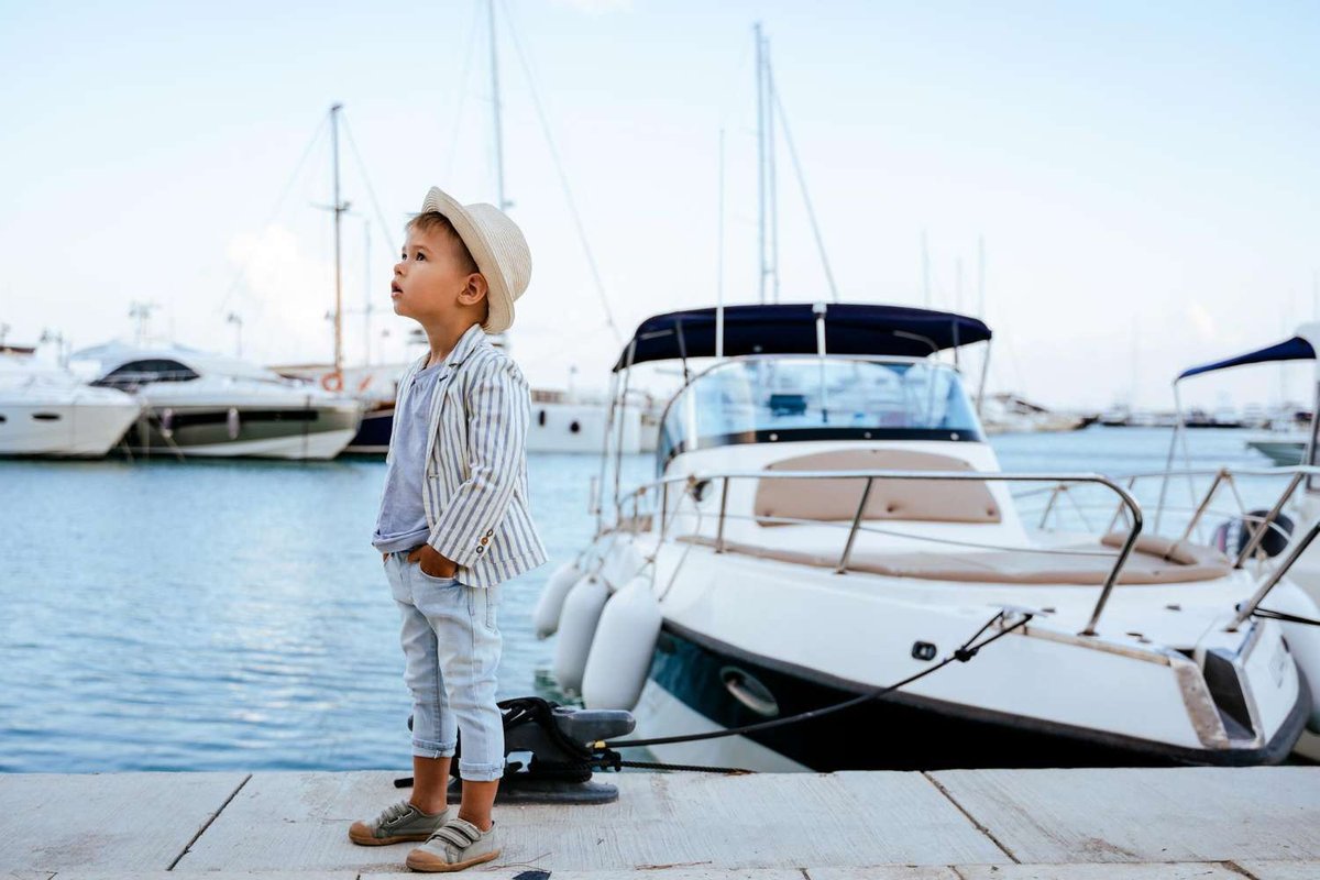 a boy posing against the backdrop of a yacht
