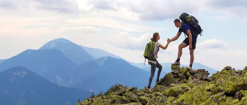 a man and a woman climb to the top of a mountain