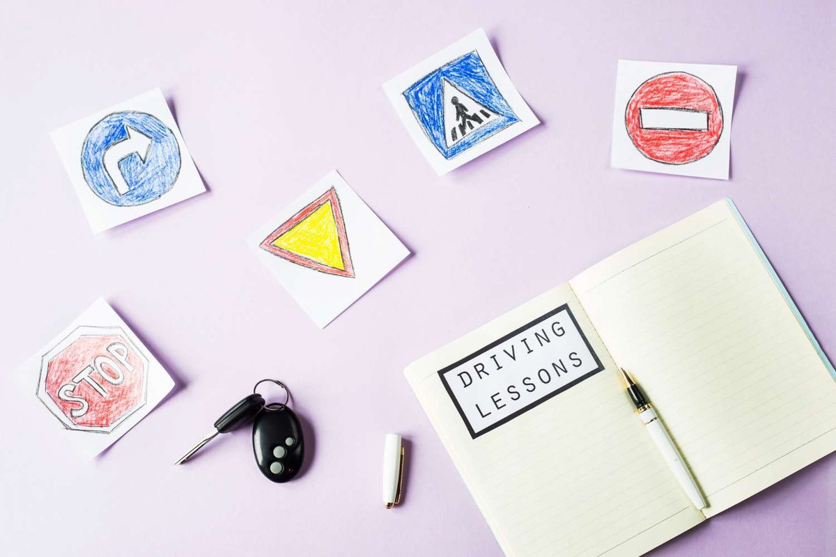 a notebook, drawings of road signs and car keys on a table
