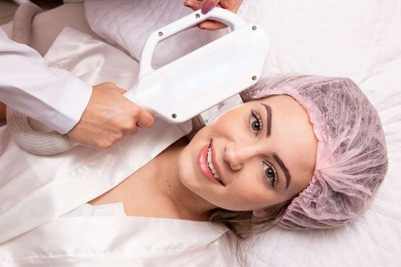 Smiling girl during a cosmetic procedure using special equipment.