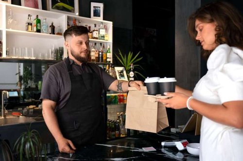 The barista gives the client a gift from the establishment.