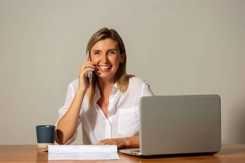 A girl is talking on the phone at the computer