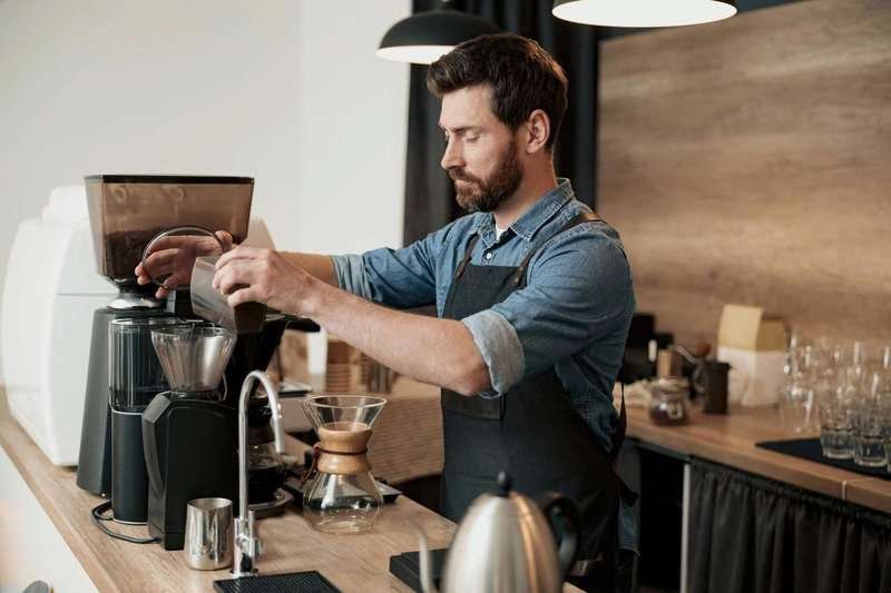 handsome-barista-grinds-coffee-beans-in-coff.max-800x600