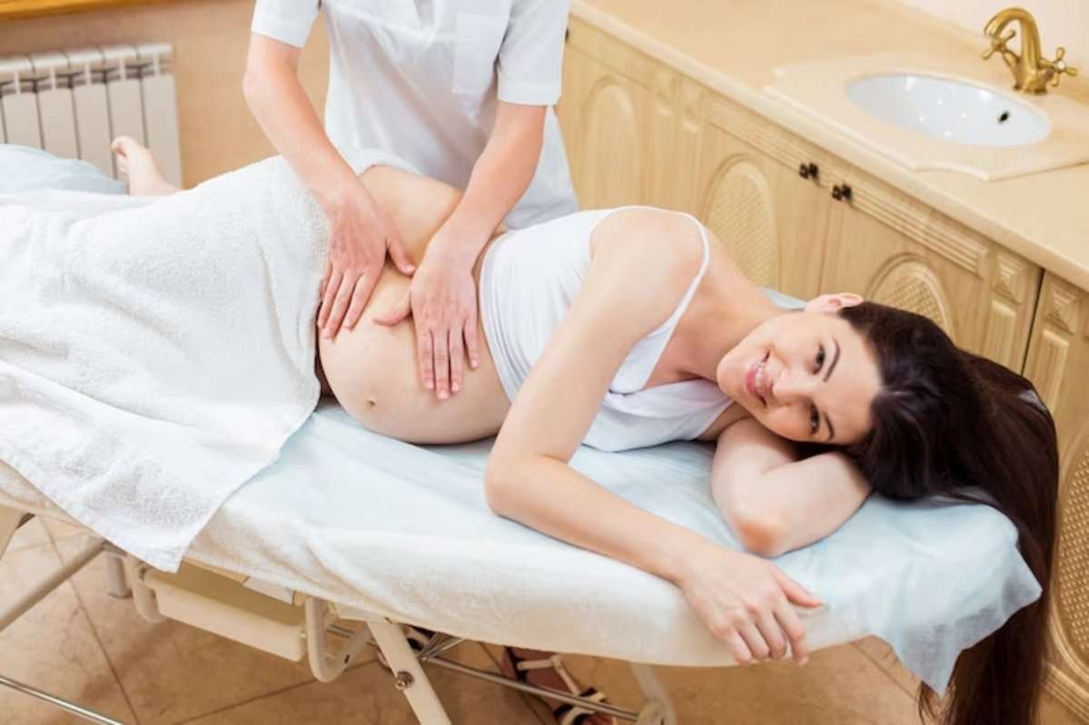Массажист делает массаж беременной девушке