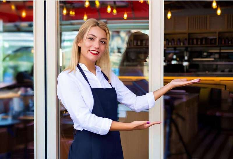 The waiter invites guests to enter the restaurant