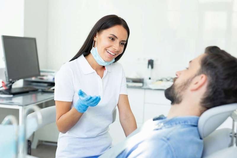 smiling-dentist-talking-with-male-client-in-.max-800x600