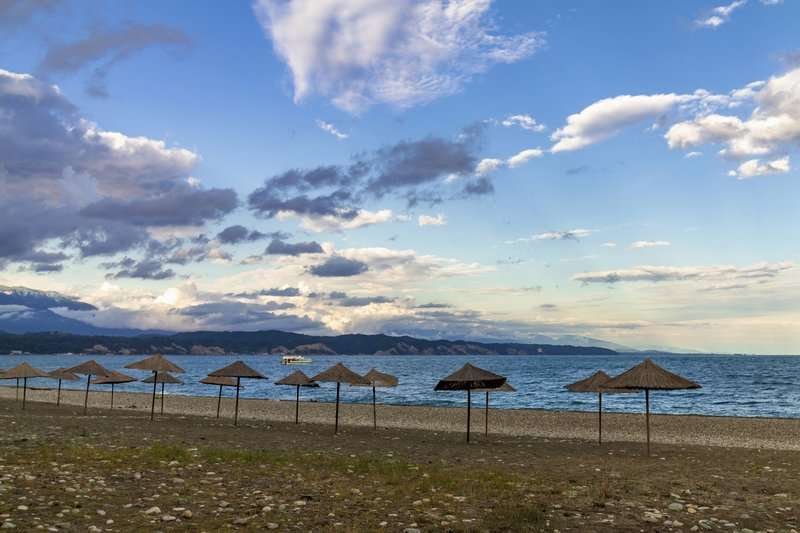 Straw beach umbrellas on the Black Sea shore in Pitsunda at sunset