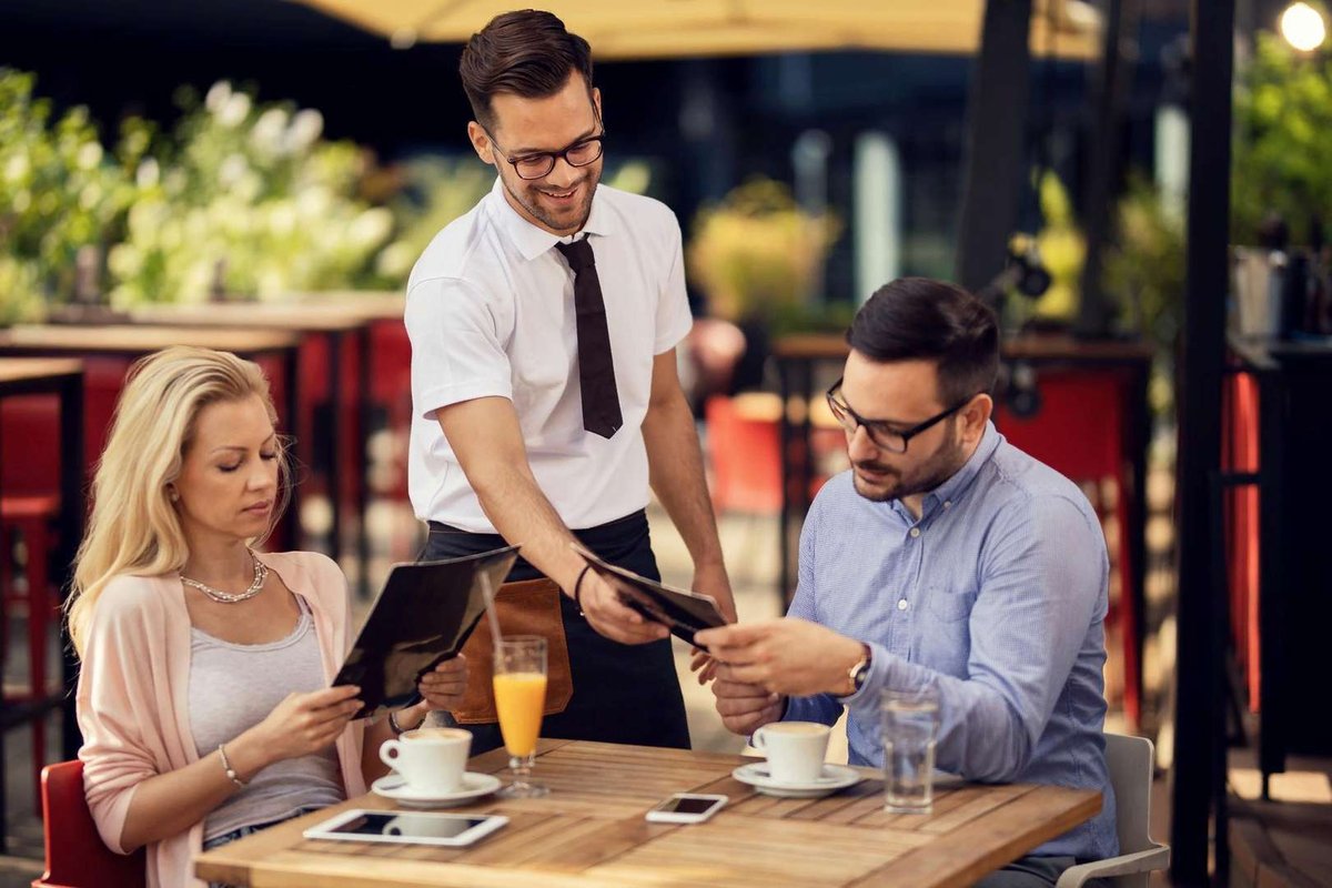 waiter-giving-a-menu-to-his-guest-in-restaurant