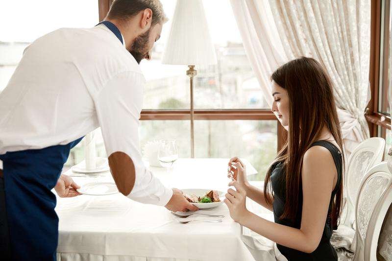 waiter restaurant is serving young lady meal