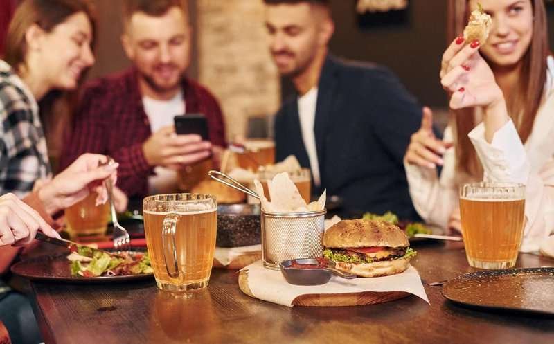 a group of friends eat burgers and drink beer