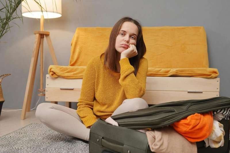 A girl is sitting next to a suitcase