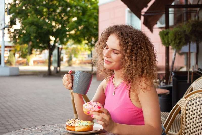 A young girl enjoys sweets outside a cafe